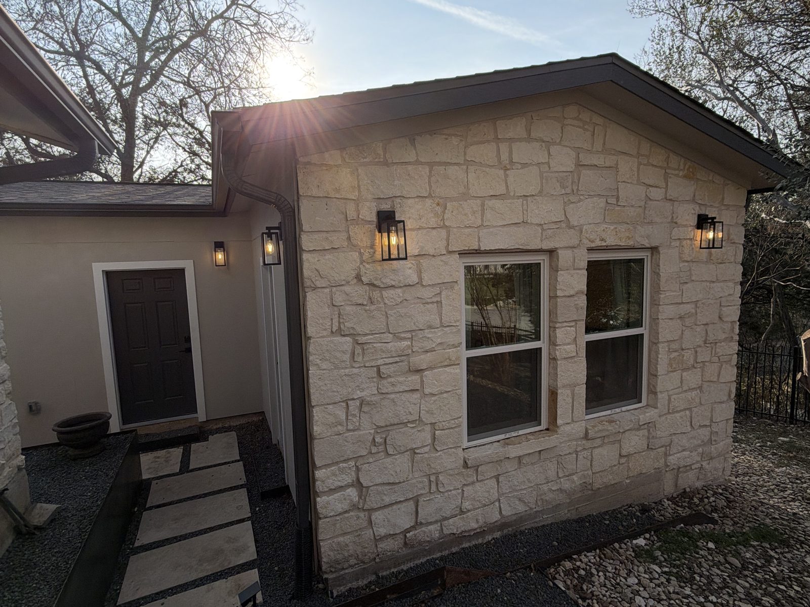 Detached stone ADU exterior in Austin with warm porch lights