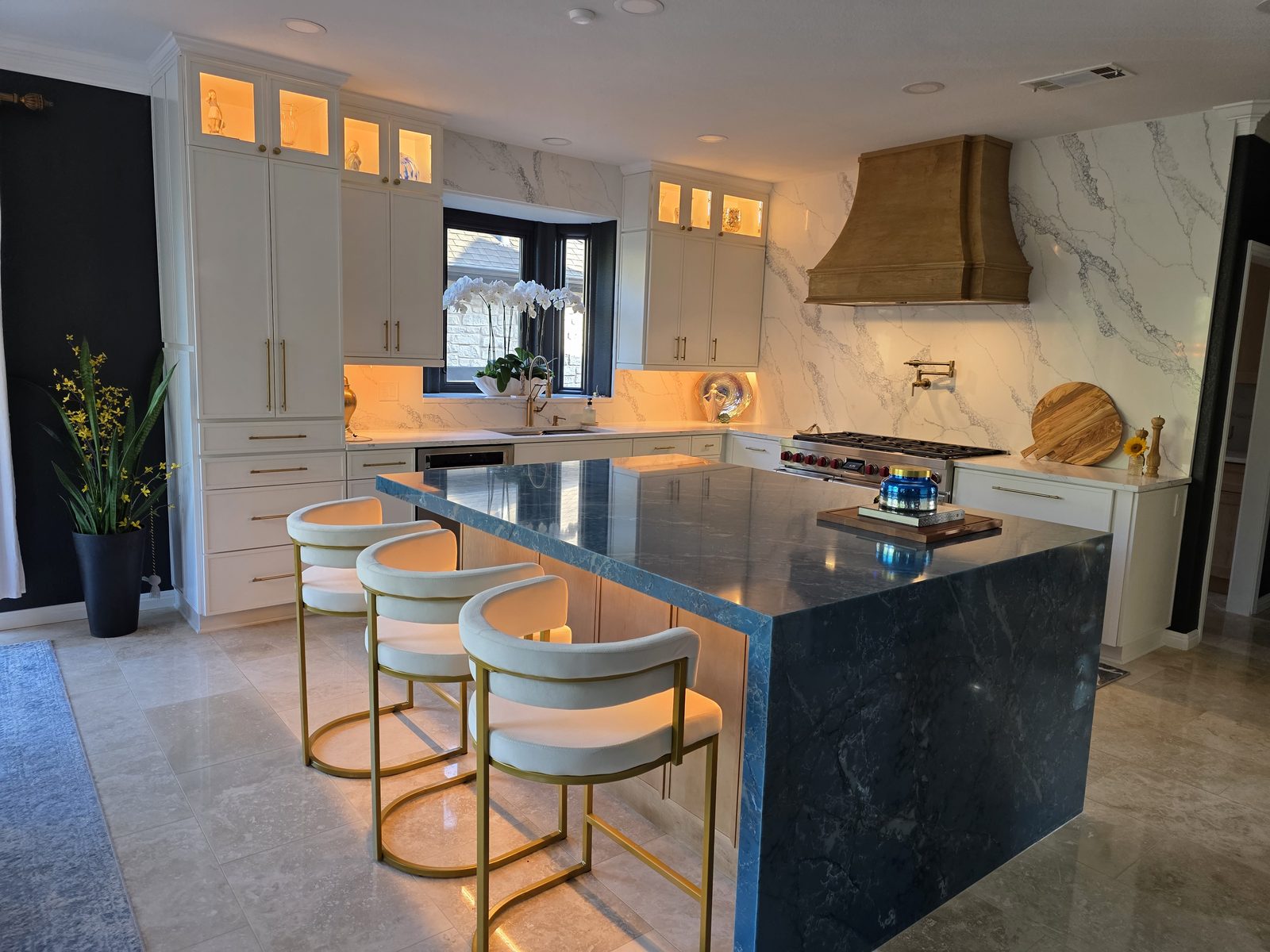 White custom kitchen cabinets with a dark island and brass range hood in Austin