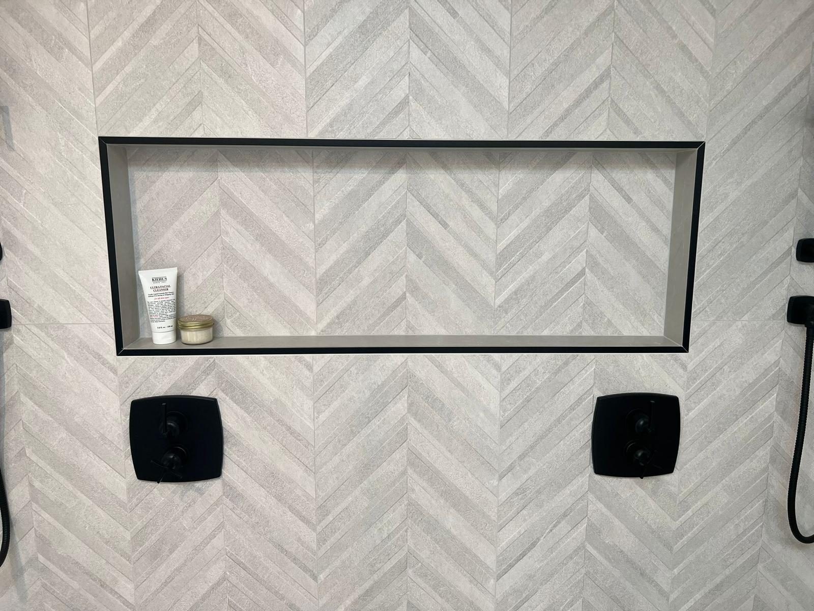 Chevron tile shower niche with black trim in a remodeled Austin bathroom